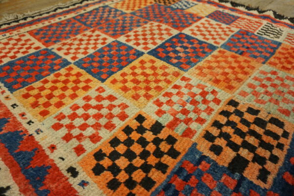 Textured rug with multicolored squares containing smaller red, blue, black, and orange checkerboards.