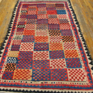 Red, blue, and orange square checkerboard rug with a textured pile on light wood flooring.