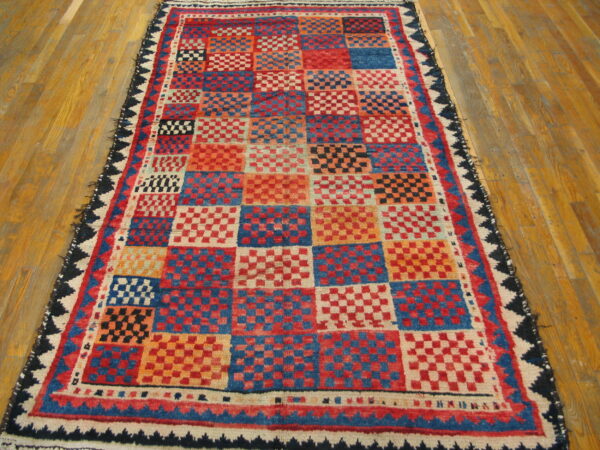 Red, blue, and orange square checkerboard rug with a textured pile on light wood flooring.