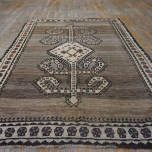 Grayish-brown geometric rug with a cream central medallion and multi-colored border on distressed wood floors.