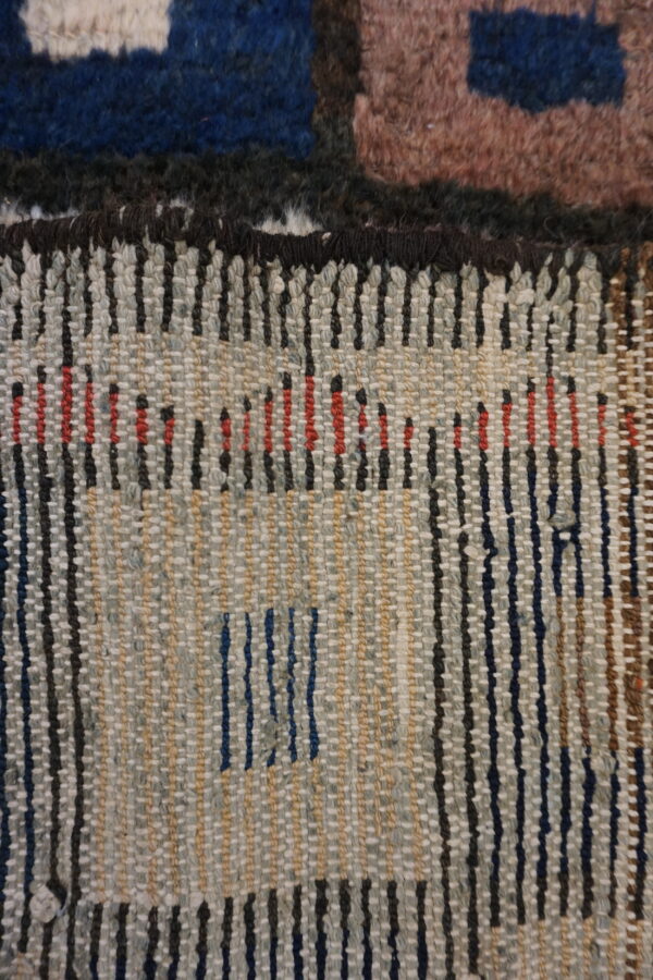 Close-up detail showing the high-pile surface meeting the flat-woven reverse side with multicolored dashed patterns.