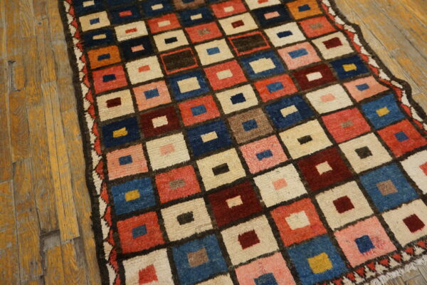 High-pile rug with a checkered design of red, blue, and cream squares over rustic wood flooring.