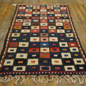 Runner rug with a high-pile, multicolored geometric square pattern on rustic wood floorboards.