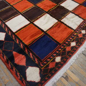 Rust, brown, white, and navy square patterned rug with thick pile shown on weathered wood flooring.