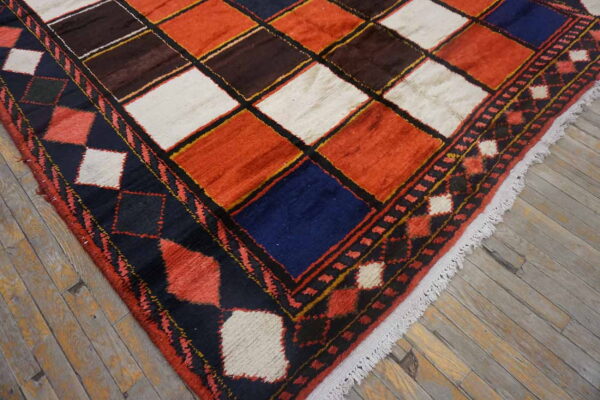 Rust, brown, white, and navy square patterned rug with thick pile shown on weathered wood flooring.