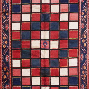 Area rug with a checkered design in red, navy, and cream, framed by a wide navy blue floral border.