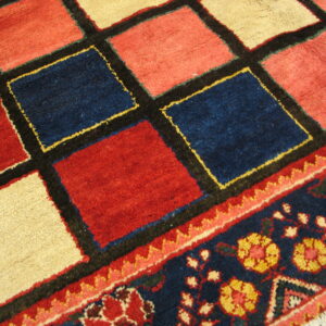 Red, navy, and cream geometric rug pattern flows into a dark blue floral border on wood flooring.