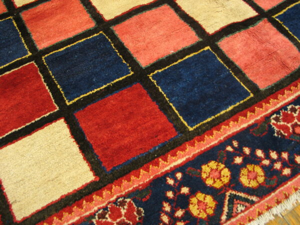 Red, navy, and cream geometric rug pattern flows into a dark blue floral border on wood flooring.
