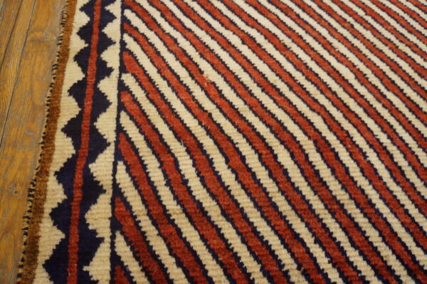 Red and cream diagonal stripes meet a navy zig-zag border on a distressed wood floor.