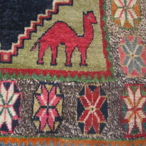 Geometric rug detail featuring a red camel on olive green and colorful medallions on a mottled brown ground.