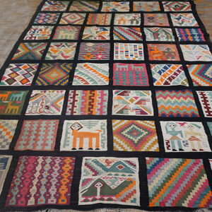 Flatweave rug displaying many small, unique, brightly colored geometric and figurative panels bordered by black.