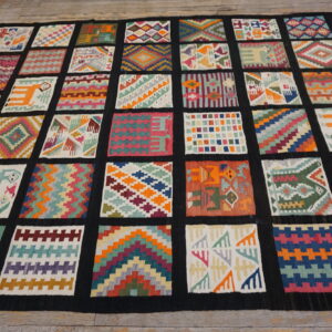 Flatwoven rug featuring a grid of diverse colorful geometric and figural patches on wooden flooring.