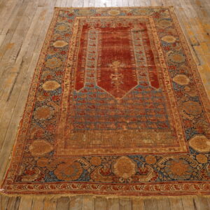 Distressed traditional rug in deep red, blue, and gold resting on rustic wood flooring.
