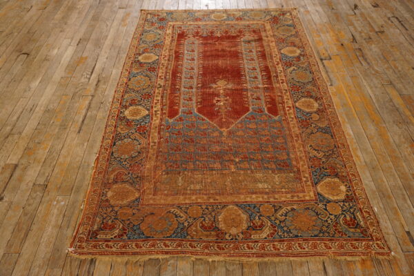 Distressed traditional rug in deep red, blue, and gold resting on rustic wood flooring.