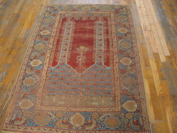 Low-pile, distressed red and blue traditional rug with ornate patterns rests on light wood floors.