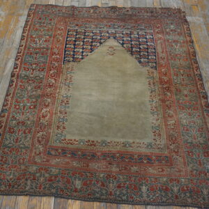 Low-pile rug featuring a stepped arch design in sage, red, and blue on rustic gray floorboards.