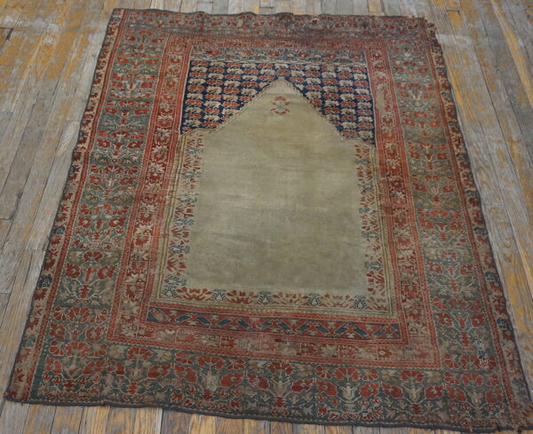 Low-pile rug featuring a stepped arch design in sage, red, and blue on rustic gray floorboards.