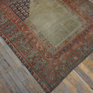 Low-pile rug with a pale center panel and patterned red, teal, and blue borders on wooden flooring.