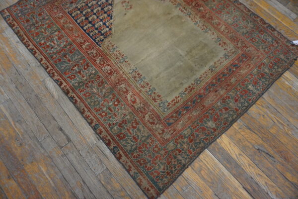 Low-pile rug with a pale center panel and patterned red, teal, and blue borders on wooden flooring.