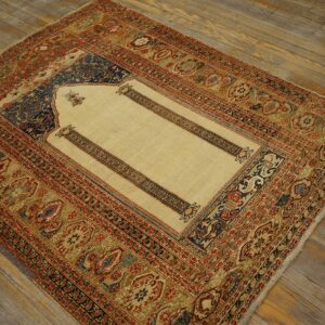 Cream, red, and blue low-pile rug with a detailed niche pattern resting on distressed wood planks.