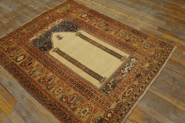 Cream, red, and blue low-pile rug with a detailed niche pattern resting on distressed wood planks.