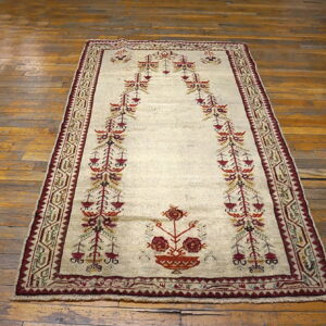 Beige rug featuring a detailed burgundy and orange stylized arch motif on distressed wood plank flooring.
