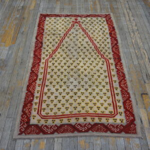 Cream and red rug with geometric motifs and a central arched design on rustic wooden flooring.