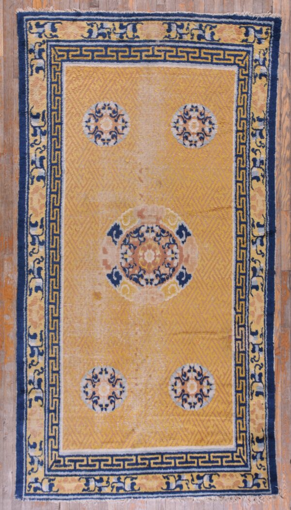 Gold and navy rug featuring a central medallion and four corner motifs, framed by a fret pattern border.