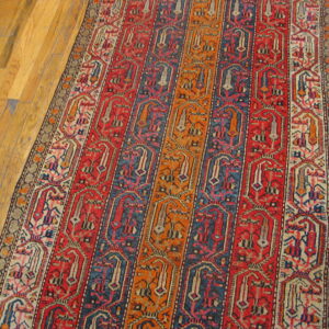 Runner rug with vertical stripes of red, blue, and orange geometric patterns on light hardwood floors.