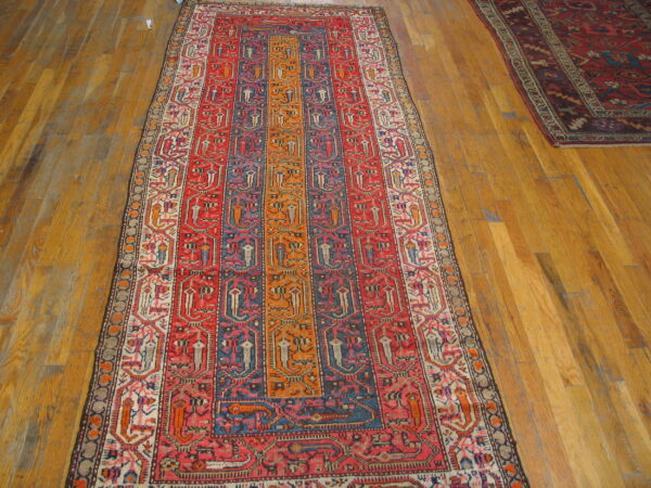 Red, blue, and orange striped geometric runner rug displayed on honey-toned hardwood planks.