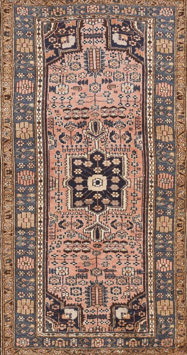 Runner rug with a dusty rose field, a dark central geometric motif, and navy and tan patterned borders.