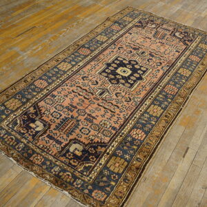 Rectangular low-pile rug with a peach and dark blue geometric pattern sits on rustic wood planks.