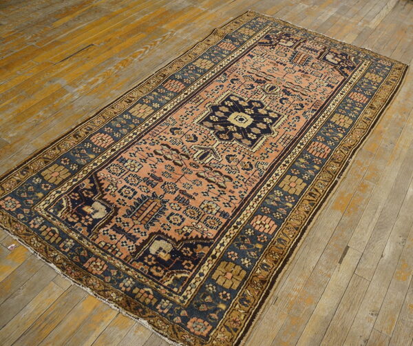 Rectangular low-pile rug with a peach and dark blue geometric pattern sits on rustic wood planks.