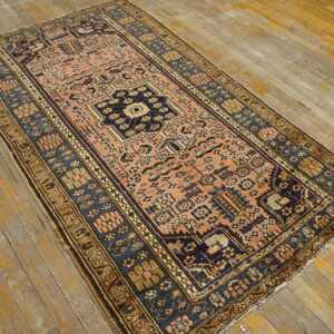Low-pile rug in coral and navy blue with geometric patterns rests on heavily distressed wooden planks.