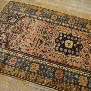 A terracotta and navy runner rug with complex tribal patterns lies on distressed wooden flooring.