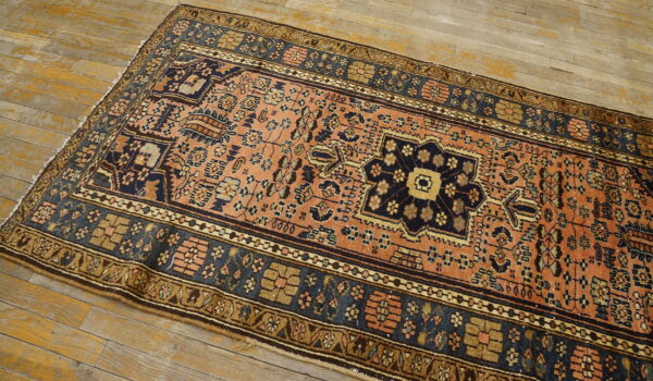 A terracotta and navy runner rug with complex tribal patterns lies on distressed wooden flooring.