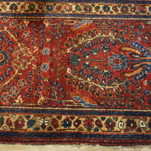The high-detail red rug displays intricate blue and beige floral motifs and decorative borders on wood planks.