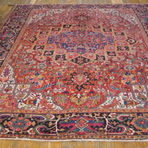Large red and navy blue oriental rug with a complex central medallion pattern on light wood plank flooring.