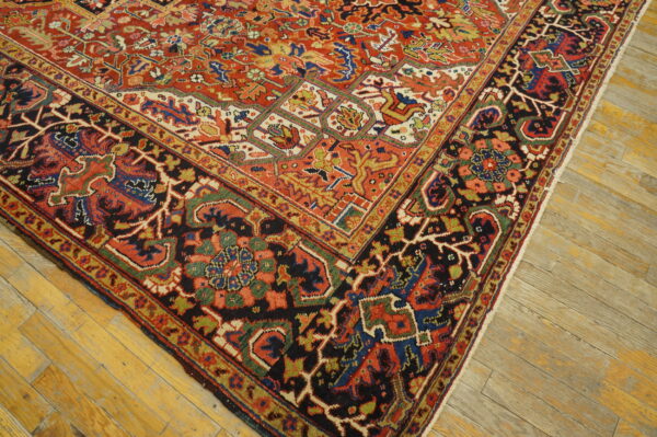 A detailed rug featuring red, black, blue, and gold geometric motifs on distressed light wood planks.
