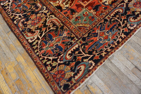 Ornate red, navy, and teal rug with complex borders rests on weathered wood plank flooring.