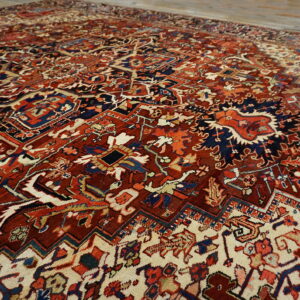 Intricate traditional rug with deep red and navy motifs contrasting against a cream background on wood floors.