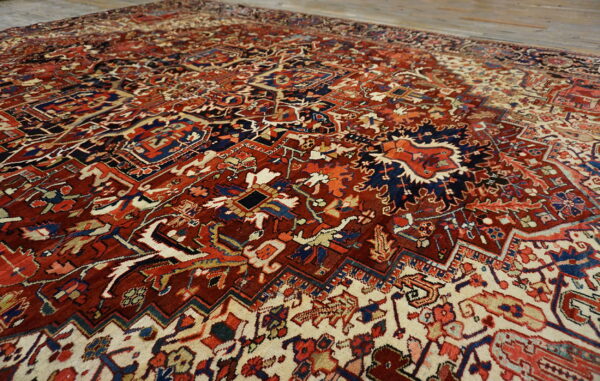 Intricate traditional rug with deep red and navy motifs contrasting against a cream background on wood floors.