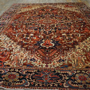 Complex traditional rug in deep red, navy blue, and ivory with an ornate central medallion on wood flooring.