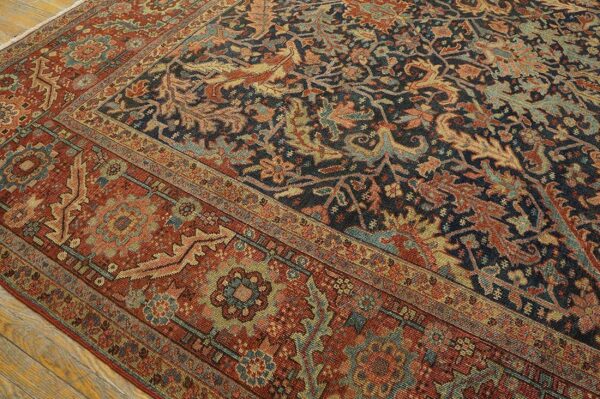 Low-pile traditional rug with navy and rust floral designs resting on light wood plank flooring.
