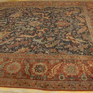 Dark blue and rust traditional area rug featuring dense floral patterns on light wooden flooring.