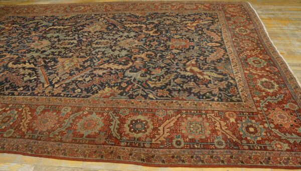 Dark blue and rust traditional area rug featuring dense floral patterns on light wooden flooring.