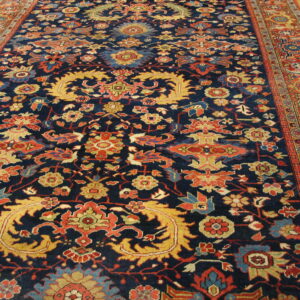 Traditional navy rug featuring ornate red, gold, and light blue botanical designs on wood floor.