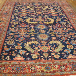 Traditional navy and red rug with dense floral patterns covers hardwood plank flooring.