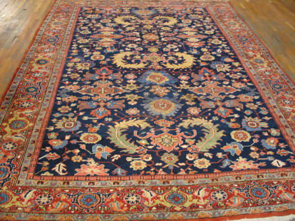 Traditional navy and red rug with dense floral patterns covers hardwood plank flooring.