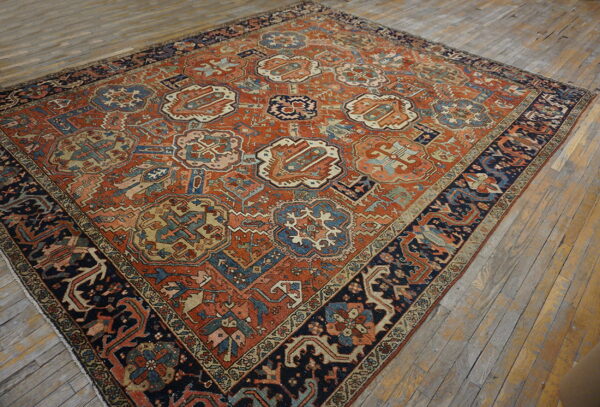 Square rug featuring an all-over geometric and medallion pattern in rust, blue, beige, and black on a distressed wood floor.